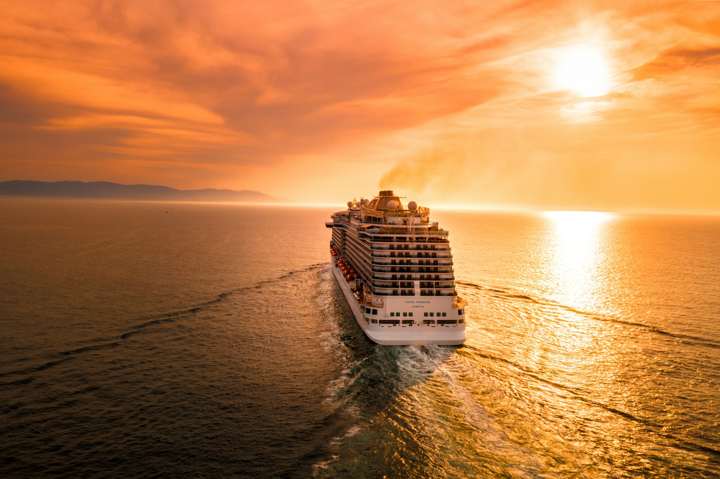 Elite luxury cruise ship sailing through crystalline Mediterranean waters at sunset